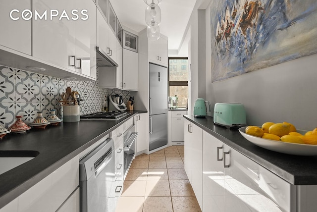 760 W End Ave Unit 6B, New York City, NY 10025 - kitchen featuring appliances with stainless steel finishes, dark countertops, decorative backsplash, ventilation hood, and white cabinetry