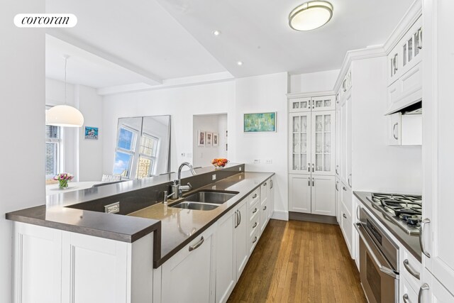 27 W 72nd St Unit 1615, New York City, NY 10023 - kitchen featuring a sink, appliances with stainless steel finishes, a peninsula, glass insert cabinets, and dark wood-style floors