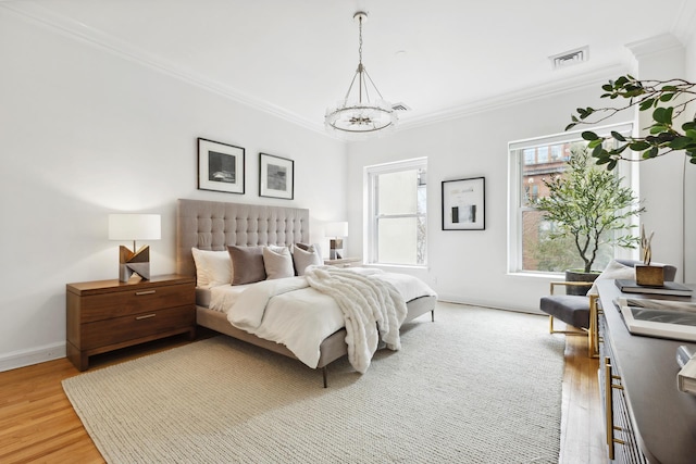 bedroom featuring crown molding, visible vents, baseboards, light wood-type flooring, and a notable chandelier