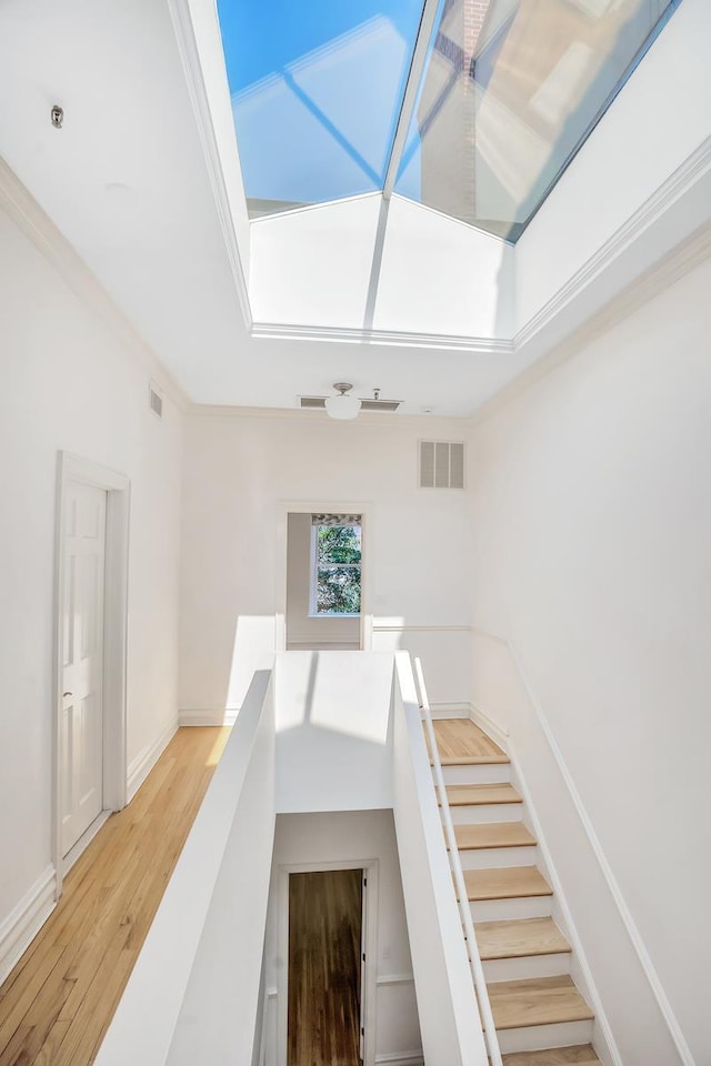 interior space featuring crown molding, baseboards, wood finished floors, and visible vents