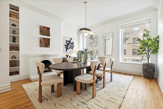 dining area with crown molding, baseboards, a brick fireplace, and hardwood / wood-style flooring