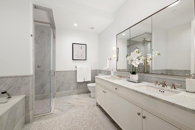 bathroom with toilet, tile walls, a shower stall, and a sink