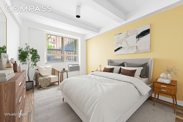 bedroom featuring beamed ceiling, wood finished floors, and baseboards