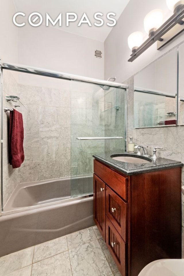 bathroom with shower / bath combination with glass door, vanity, and marble look tiles