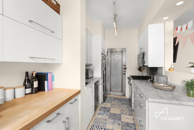 kitchen featuring stainless steel appliances, white cabinetry, recessed lighting, and wood counters