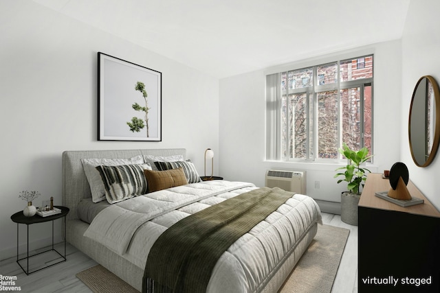 bedroom with a wall mounted air conditioner, wood finished floors, and a baseboard heating unit
