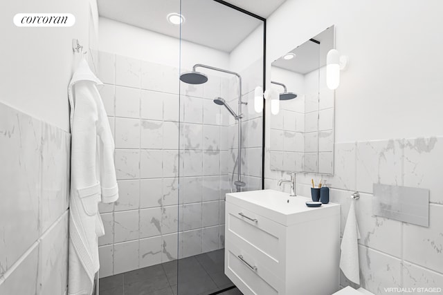 bathroom with tile walls, walk in shower, vanity, wainscoting, and tile patterned flooring