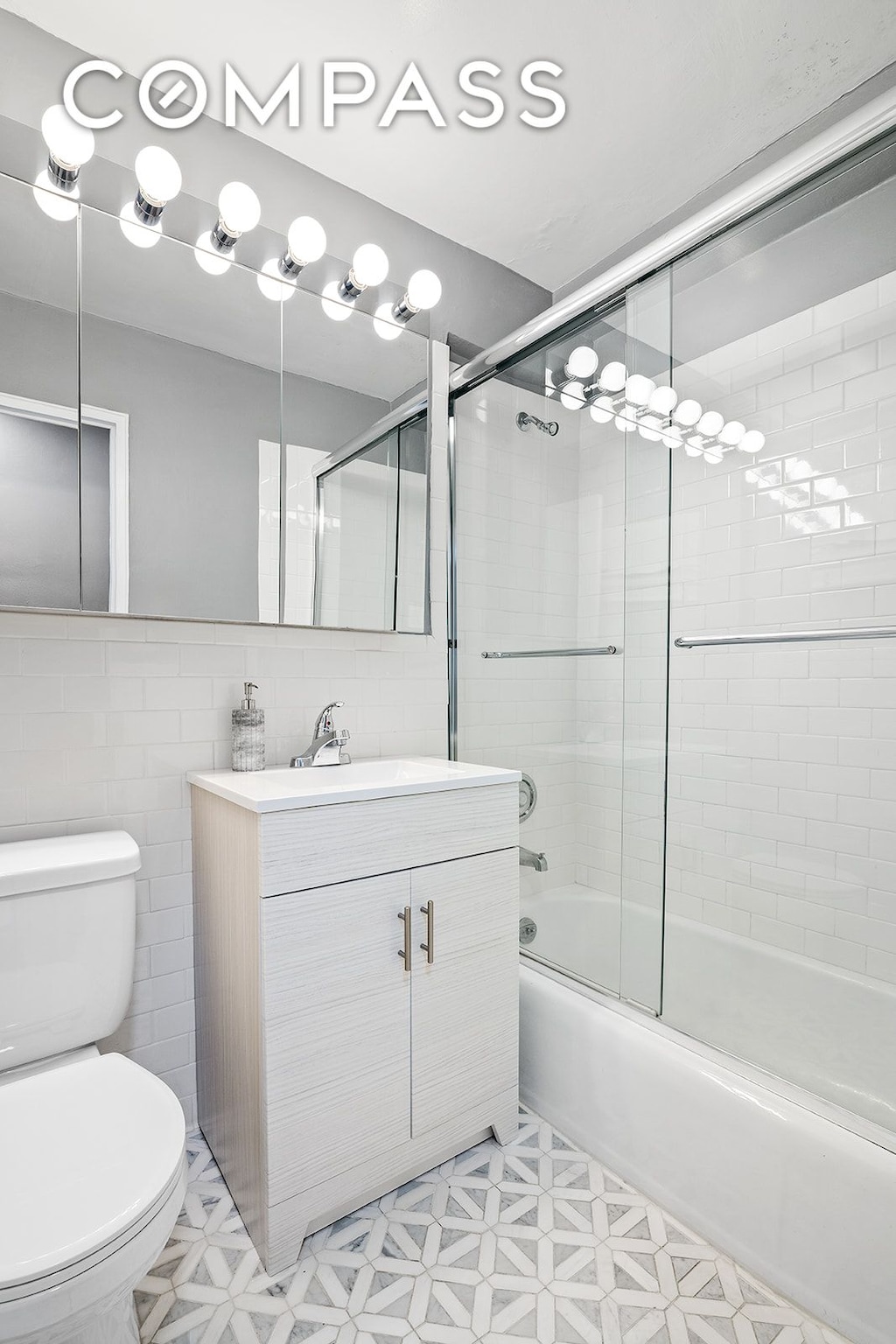 bathroom with vanity, toilet, tile walls, tile patterned floors, and enclosed tub / shower combo