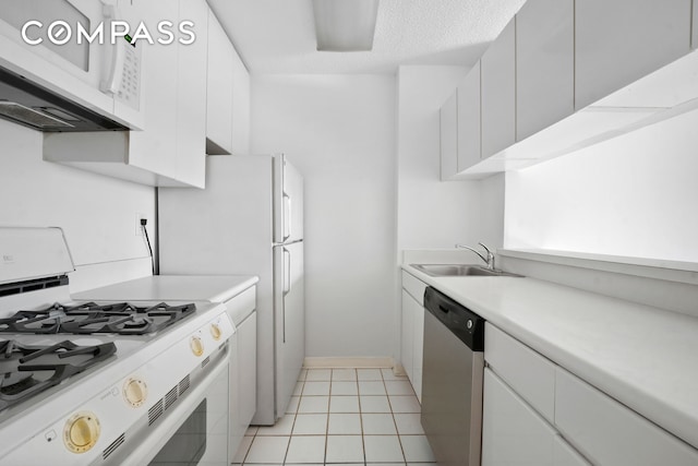 kitchen with white appliances, light countertops, white cabinetry, a sink, and light tile patterned floors