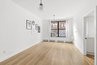14 Prince St Unit 2-F, New York City, NY 10012 - unfurnished dining area featuring light wood-style flooring, baseboards, and cooling unit