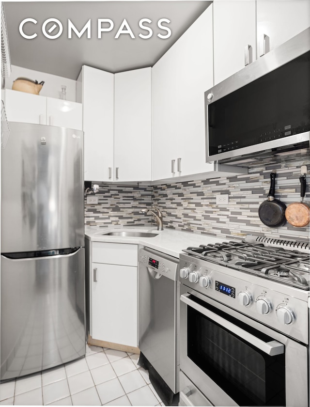 kitchen featuring stainless steel appliances, a sink, light countertops, white cabinetry, and light tile patterned flooring