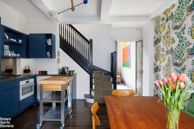 1 W 67th St Unit 309, New York City, NY 10023 - dining room with dark wood-type flooring, stairs, beam ceiling, and bar