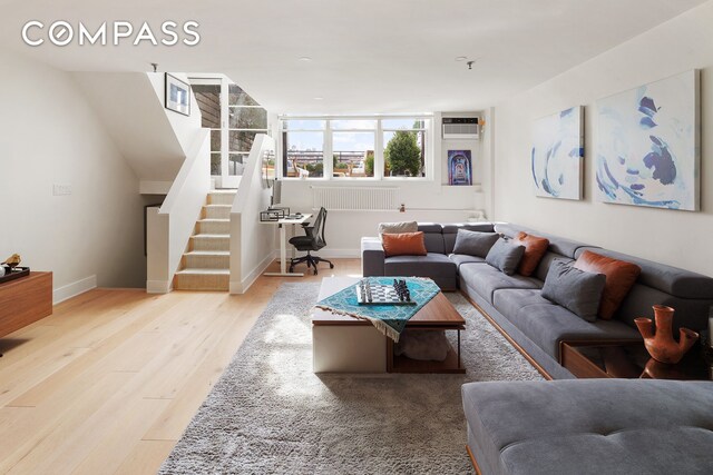 240 W 23rd St Phc, Phc, New York City, NY 10011 - living area with wood finished floors, stairway, a wall mounted air conditioner, and baseboards