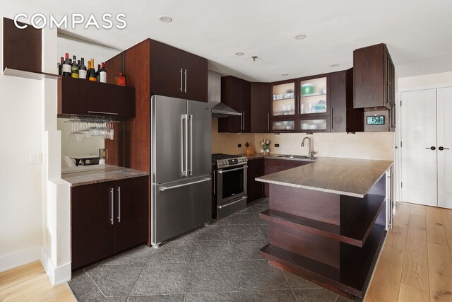 240 W 23rd St Phc, Phc, New York City, NY 10011 - kitchen with appliances with stainless steel finishes, a sink, glass insert cabinets, dark brown cabinetry, and decorative backsplash