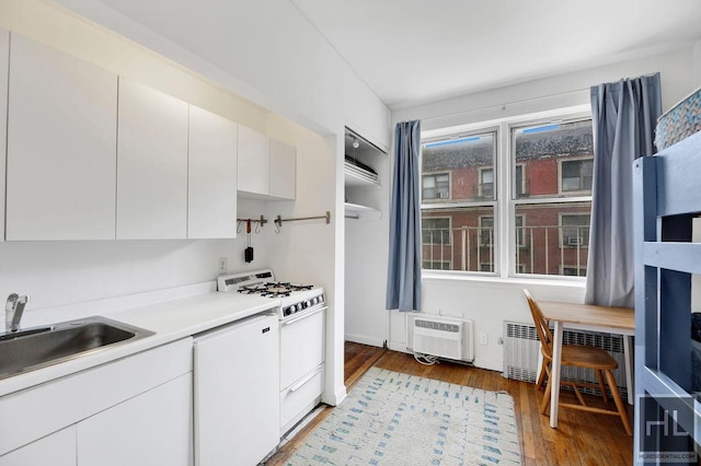 kitchen featuring white appliances, radiator, light wood-style flooring, light countertops, and a sink