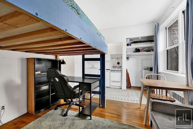 kitchen with white gas stove, a desk, and wood finished floors