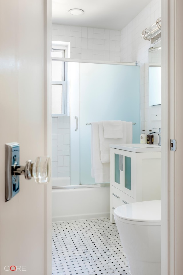 bathroom featuring bath / shower combo with glass door, vanity, and toilet