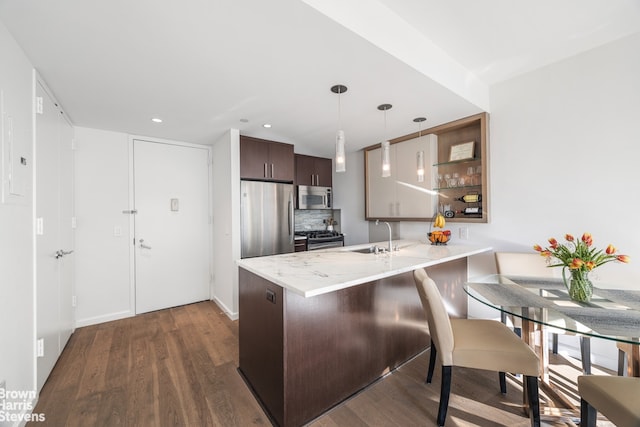 kitchen with dark wood finished floors, stainless steel appliances, a peninsula, and dark brown cabinets
