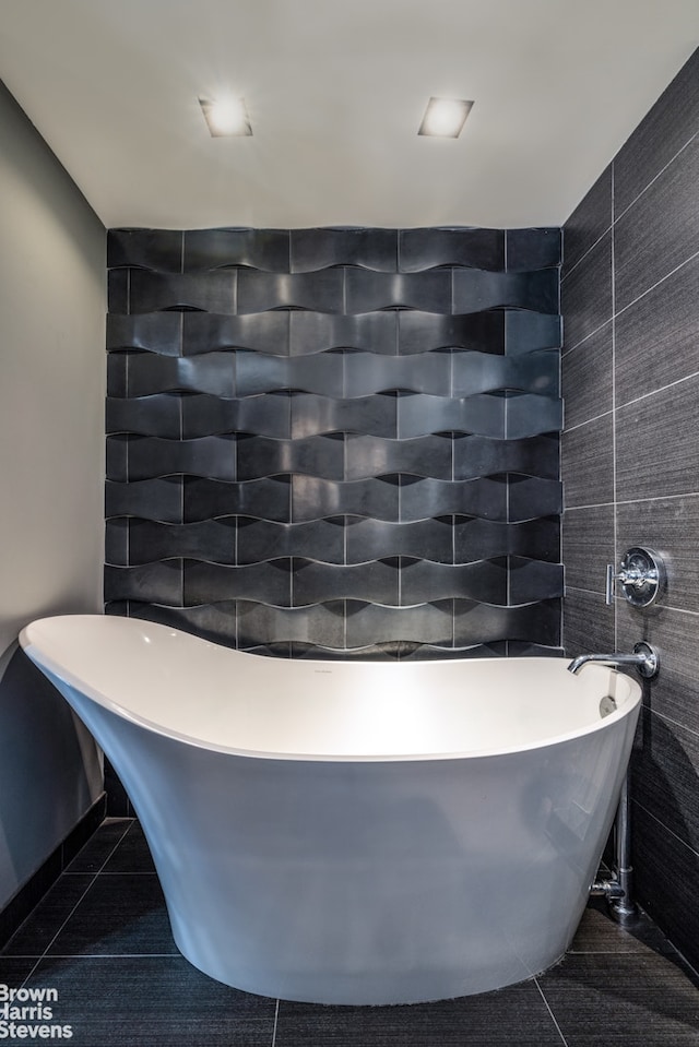 bathroom featuring tile walls, a soaking tub, and tile patterned floors