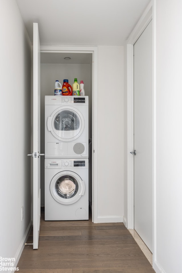 washroom featuring baseboards, laundry area, stacked washer / dryer, and wood finished floors