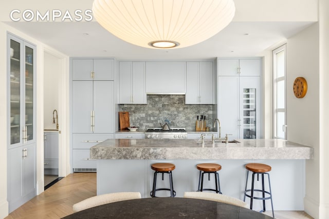 250 E 21st St Unit 10A, New York City, NY 10010 - kitchen with a sink, a kitchen breakfast bar, tasteful backsplash, range, and glass insert cabinets