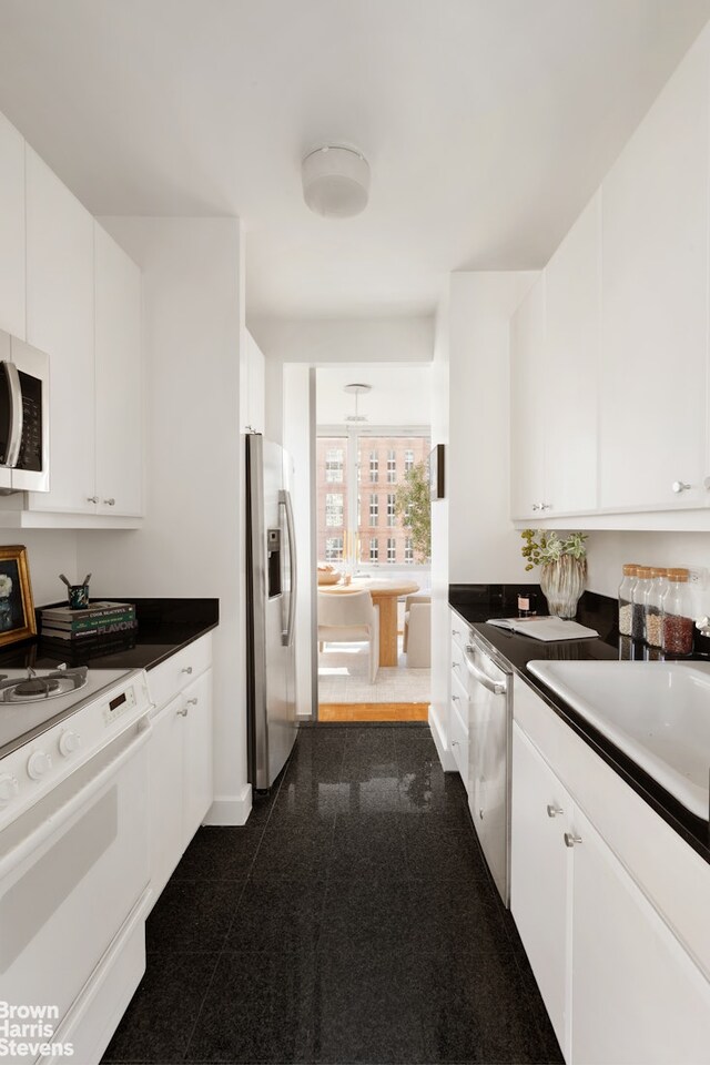 150 Columbus Ave Unit 18F, New York City, NY 10023 - kitchen featuring white cabinetry, granite finish floor, stainless steel appliances, and dark countertops