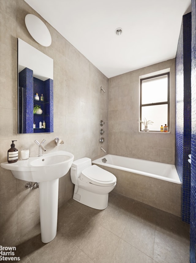 bathroom with tile patterned flooring, tile walls, toilet, and shower / washtub combination