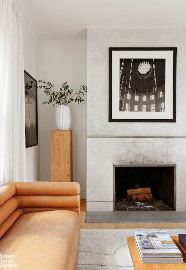 living room featuring a fireplace, crown molding, and wood finished floors