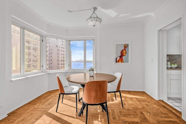 dining space with baseboards, a notable chandelier, and ornamental molding