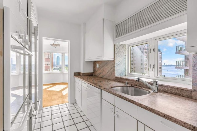 kitchen with light stone countertops, decorative backsplash, white cabinets, white appliances, and a sink