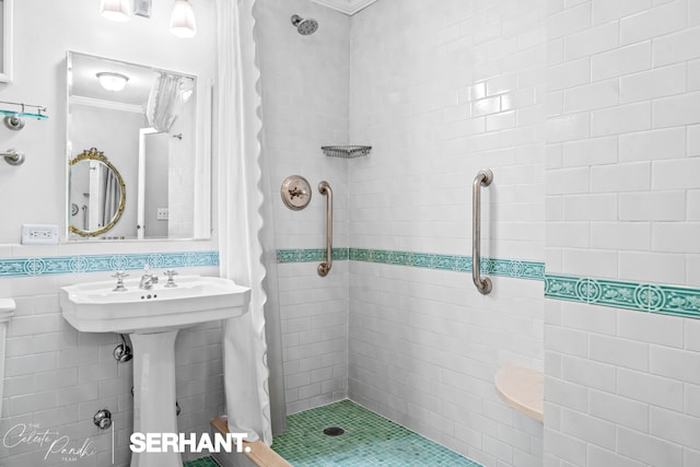 bathroom with ornamental molding, tiled shower, tile walls, and a sink