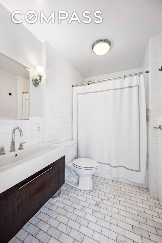 bathroom with toilet, vanity, and tile walls