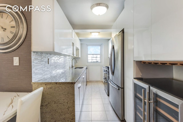 520 E 76th St Unit 11C, New York City, NY 10021 - kitchen featuring wine cooler, appliances with stainless steel finishes, white cabinetry, a sink, and light tile patterned flooring