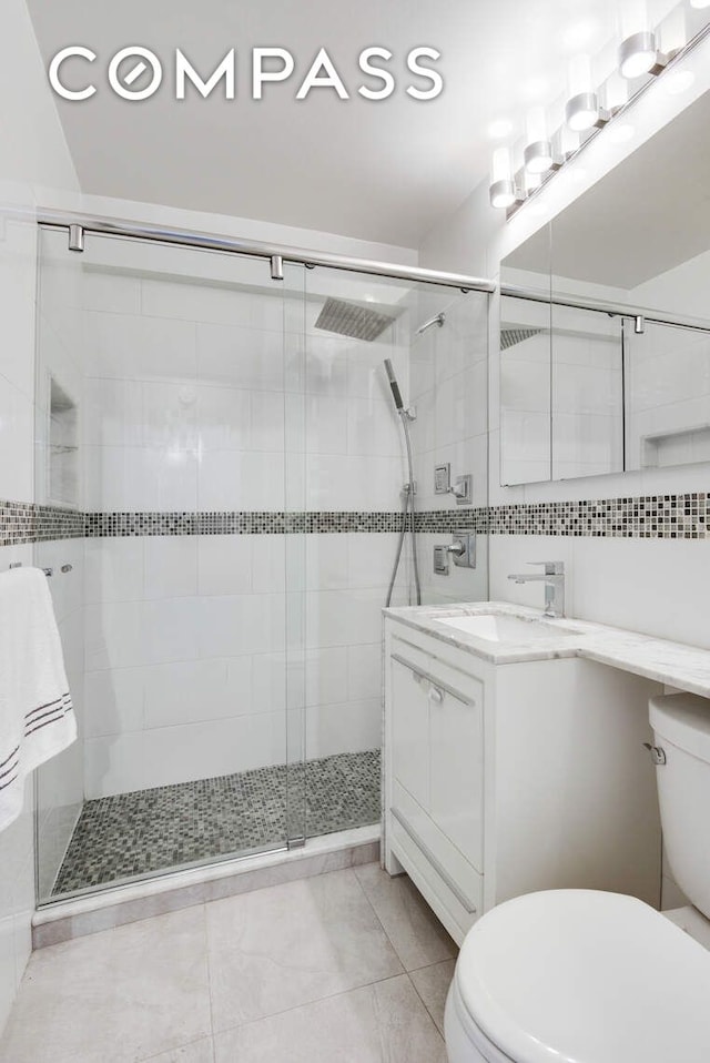520 E 76th St Unit 11C, New York City, NY 10021 - bathroom featuring toilet, vanity, a shower stall, and tile patterned flooring