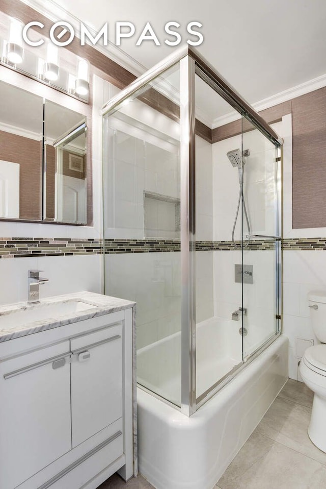 520 E 76th St Unit 11C, New York City, NY 10021 - bathroom featuring tile walls, toilet, combined bath / shower with glass door, vanity, and crown molding