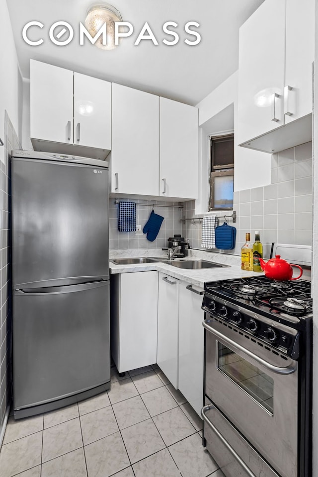 205 E 89th St Unit 4C, New York City, NY 10128 - kitchen featuring stainless steel appliances, light countertops, white cabinets, tasteful backsplash, and light tile patterned flooring