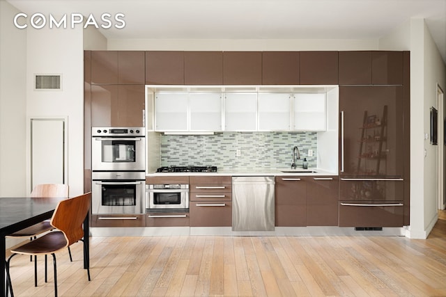 75 Wall St Unit 24M, New York City, NY 10005 - kitchen featuring a sink, stainless steel appliances, modern cabinets, and light wood finished floors