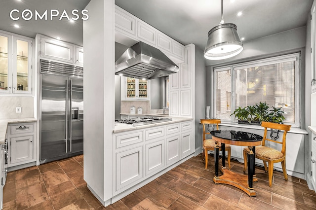 785 5th Ave Unit 3C, New York City, NY 10022 - kitchen featuring appliances with stainless steel finishes, range hood, white cabinets, glass insert cabinets, and recessed lighting