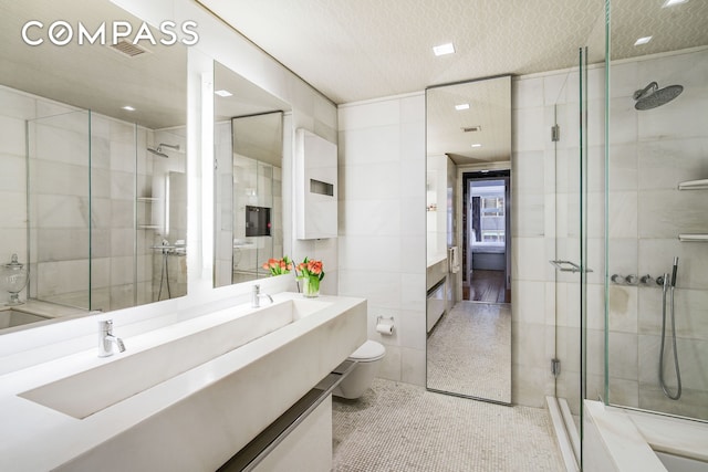 full bathroom featuring vanity, visible vents, toilet, tile walls, and a shower stall