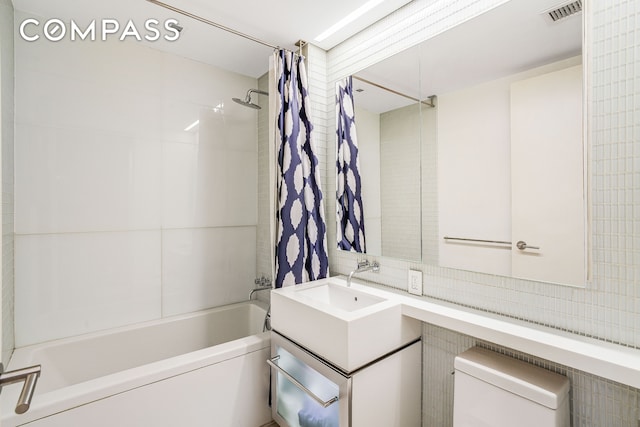 full bathroom with visible vents, shower / tub combo with curtain, vanity, toilet, and tile walls
