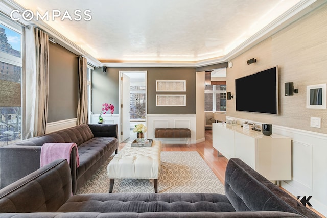 living area featuring wainscoting, wood finished floors, and a decorative wall