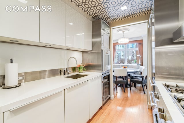 kitchen featuring modern cabinets, stainless steel gas cooktop, a sink, light countertops, and white cabinets