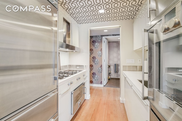 kitchen featuring light countertops, appliances with stainless steel finishes, light wood-style flooring, and white cabinetry