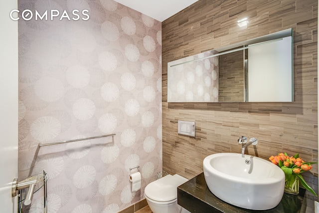 bathroom with tile walls, vanity, and toilet