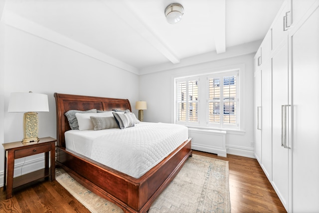 bedroom featuring beamed ceiling, dark wood-type flooring, and baseboards