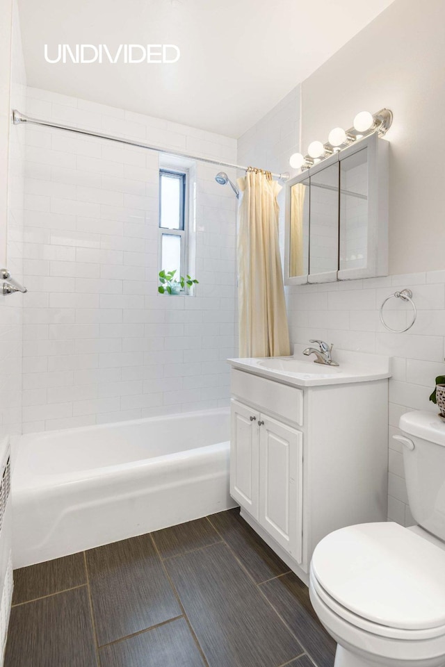 bathroom featuring vanity, shower / bath combination with curtain, toilet, and tile walls