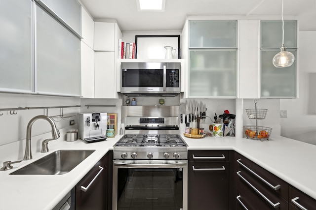 kitchen with white cabinetry, stainless steel appliances, light countertops, and a sink