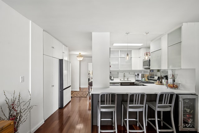 kitchen featuring modern cabinets, a peninsula, stainless steel appliances, and light countertops