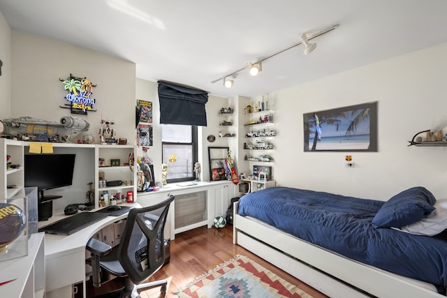 bedroom with rail lighting and wood finished floors