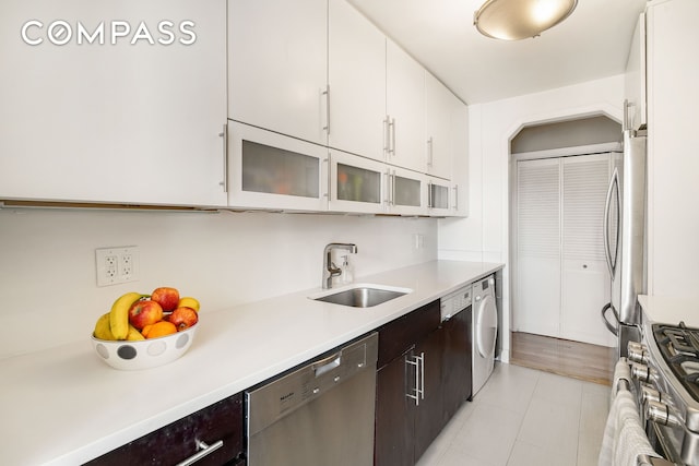401 E 86th St Unit 15C, New York City, NY 10028 - kitchen featuring stainless steel appliances, washer / dryer, dark brown cabinets, light countertops, and white cabinets